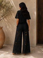 Close-up detail of the intricate embroidery on the leg of the white cotton trousers.