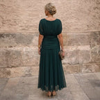 Close-up detail of the criss-cross off-shoulder neckline on the sophisticated maxi dress.
