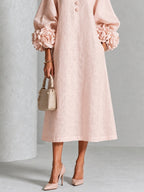 Detailed shot of the exaggerated rose-knot cuffs on the voluminous three-quarter sleeves of the dress.