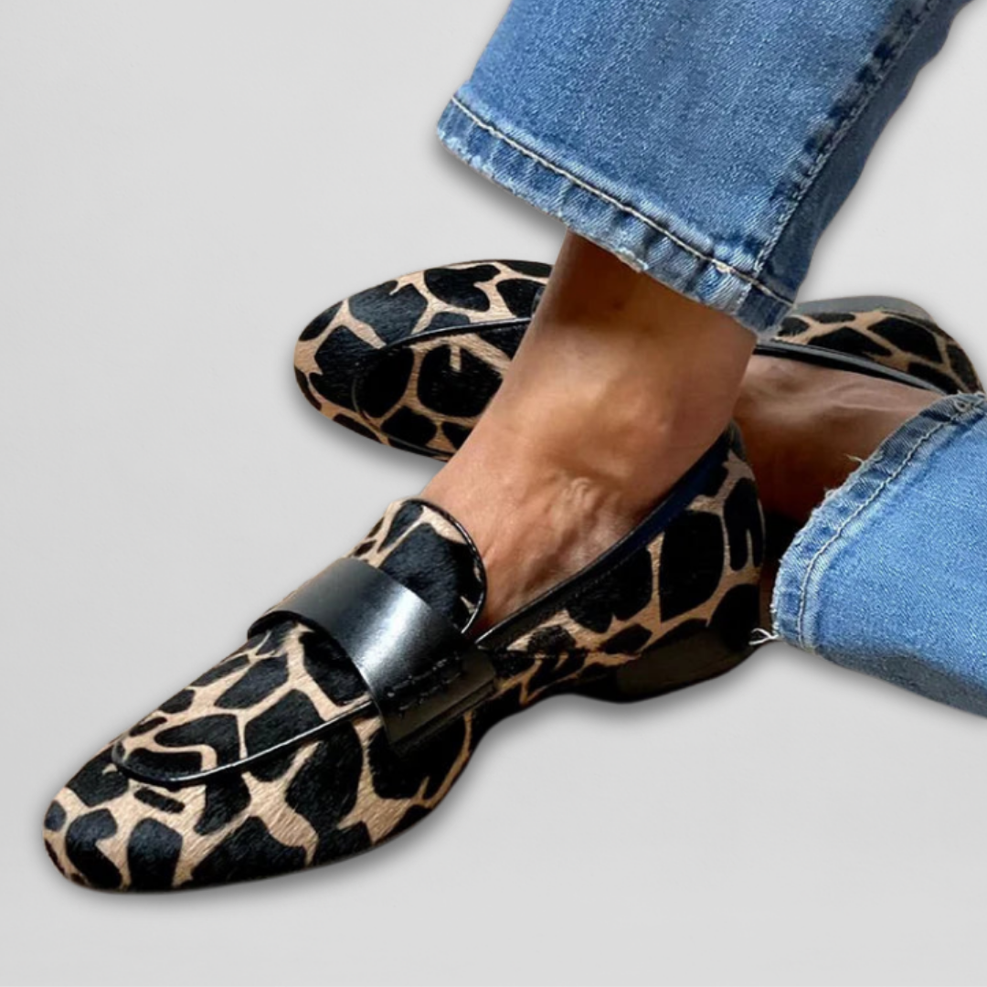 Side profile of a woman walking outdoors in a pair of stylish black women's loafers, paired with casual trousers, emphasizing all-day comfort.